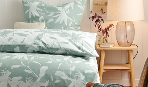 Ein Bett mit grün-weißer Microfaser-Bettwäsche.