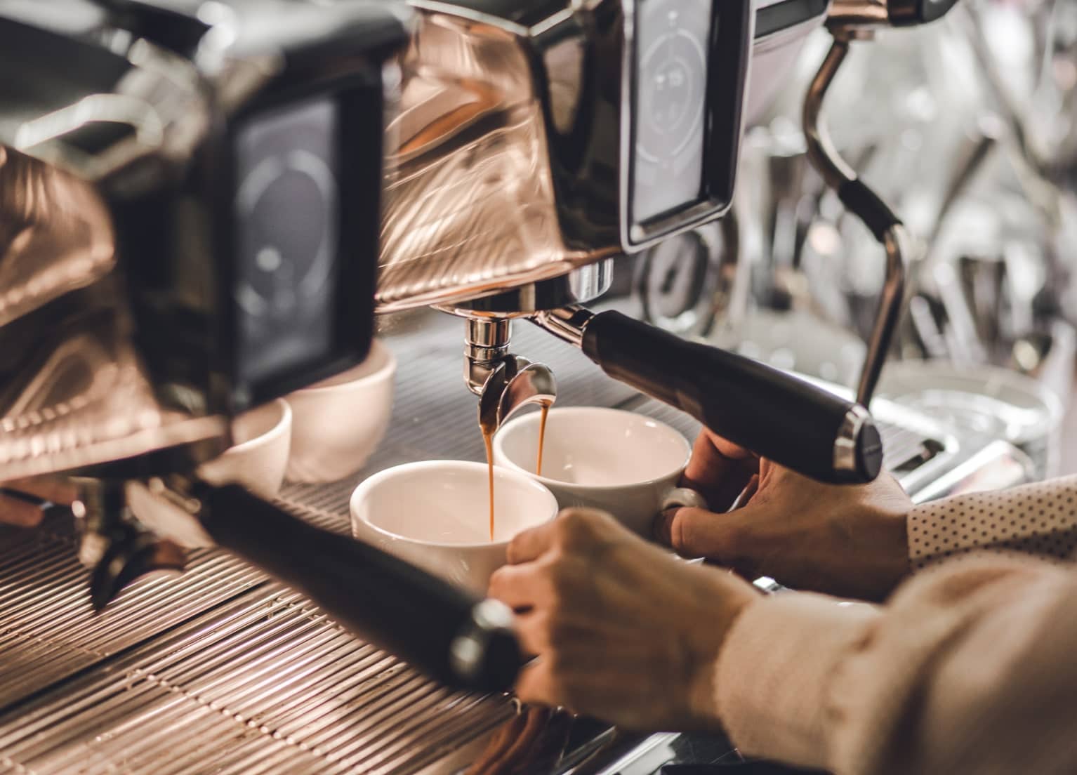 Kaffee läuft aus einem Siebträger in zwei Kaffeetassen