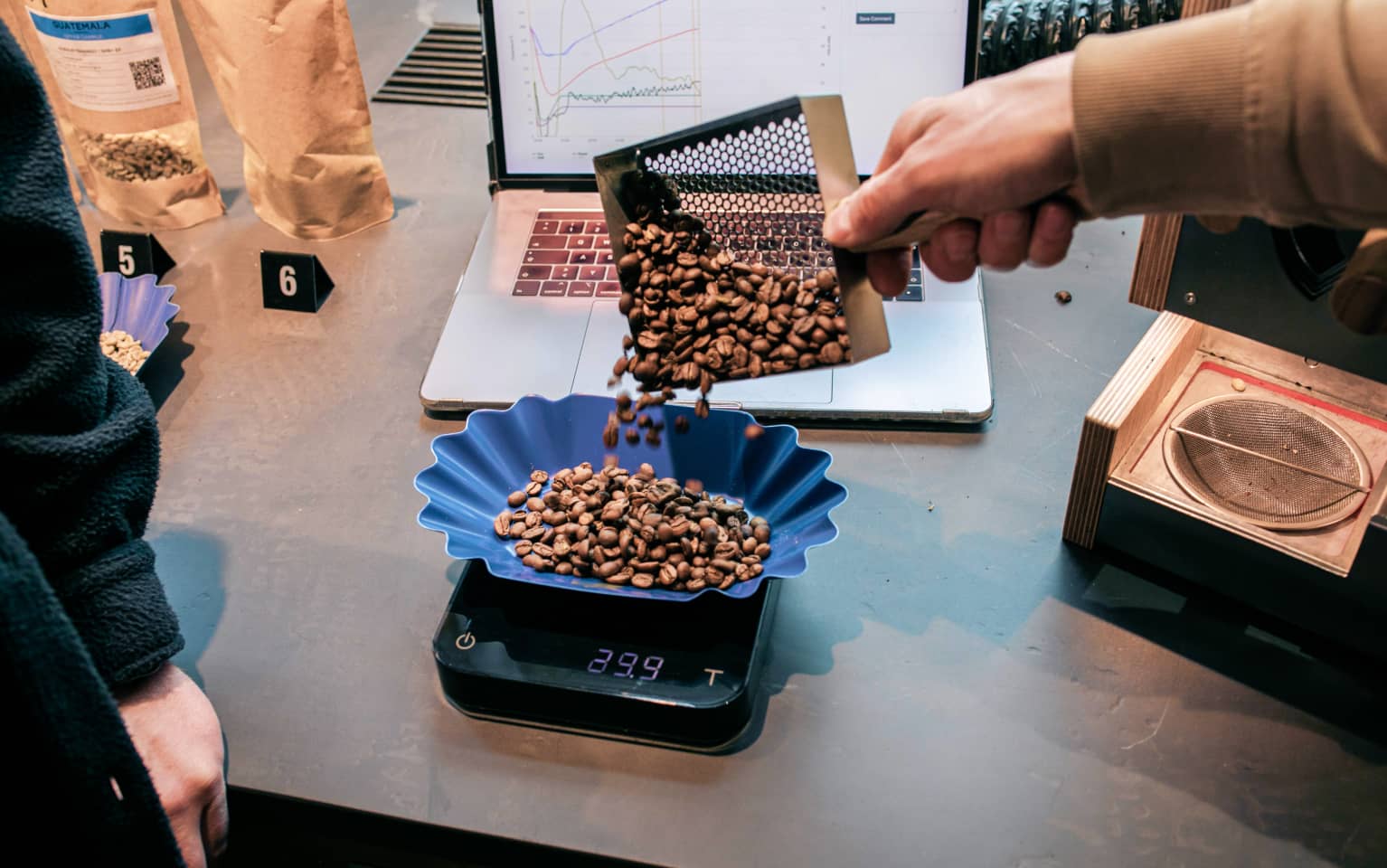Kaffeebohnen werden in eine Schaale auf einer Waage geschüttet und abgewogen
