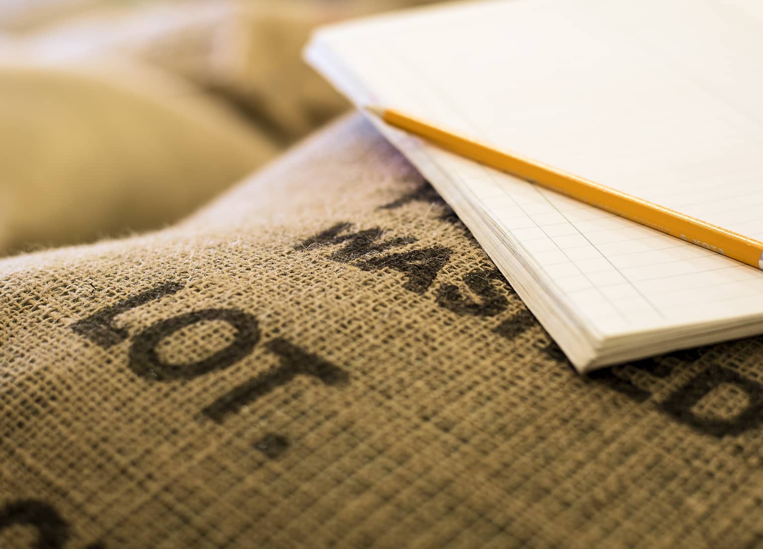 Ein Zettel und ein Stift liegen auf einem Sack mit Kaffeebohnen