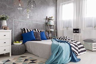 Die richtigen Möbel finden: Ein modern eingerichtetes Schlafzimmer mit einem großen Bett auf dem eine aufgeschlagene Decke und verschiedene Kissen liegen.
