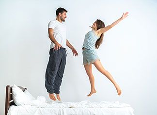 Mann und Frau springen auf einer Matratze.