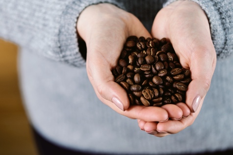 Jemand hält viele Kaffeebohnen in den Händen