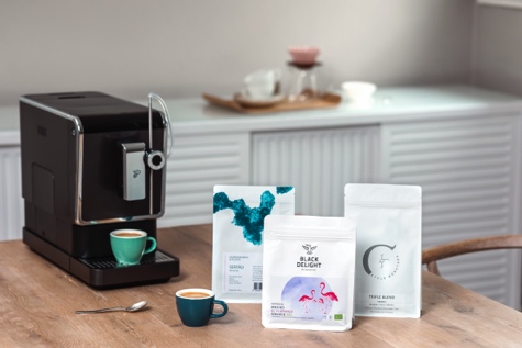 Drei Packungen Kaffee stehen neben dem Vollautomaten