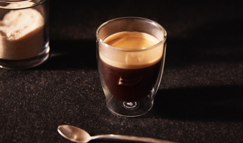 Doppelwandiges Glas mit Kaffee und Bild der Tchibo Kaffee-Sommelière.