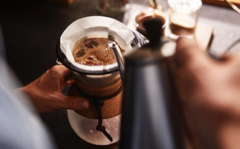 Blick von oben auf eine BODUM Pour Over, in die mit einer Schwanenhalskanne heißes Wasser gegossen wird
