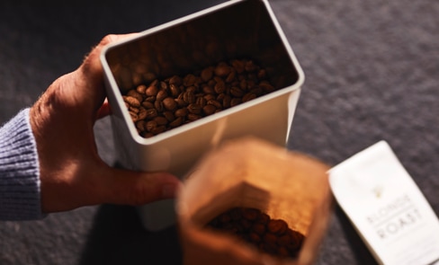 Blick von oben in eine mit Kaffeebohnen gefüllte Kaffeedose