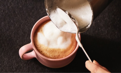 Milchschaum in Tasse gießen
