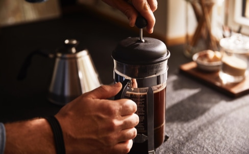 Mann drückt den Siebstempel einer BODUM Caffettiera French Press nach unten