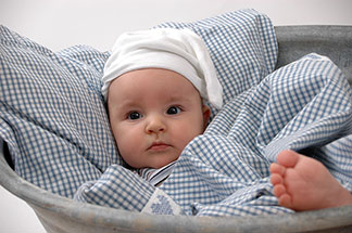 Ein Baby liegt im Bett und schaut in die Gegend.