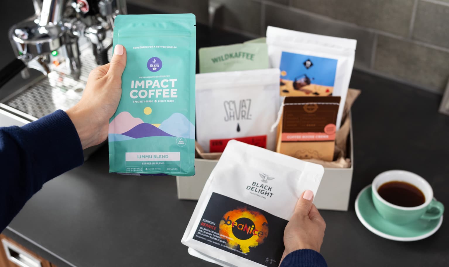Eine Hand greift in einen Karton mit mehreren Specialty Coffee Packungen.