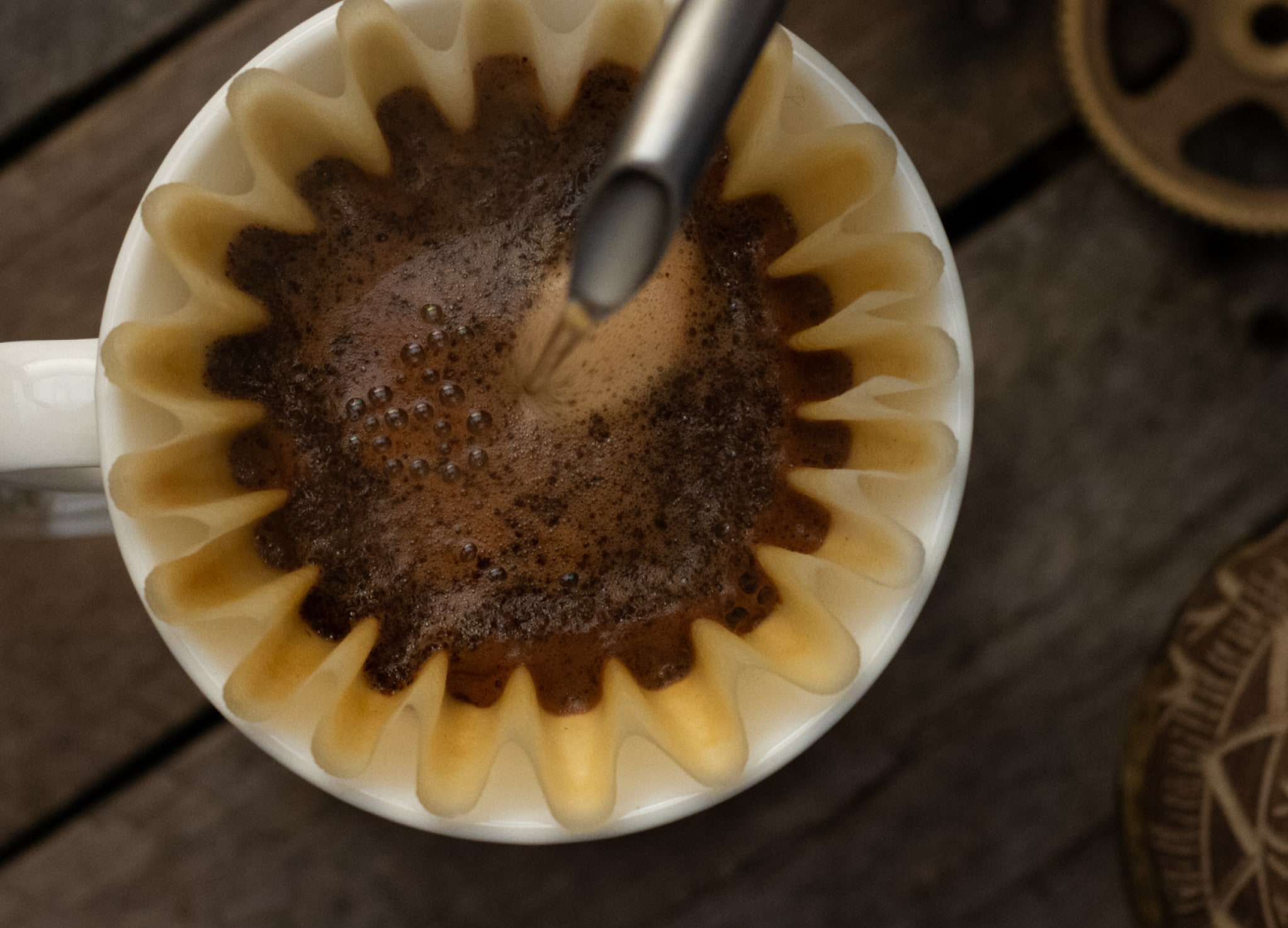 Heißes Wasser wird aus einem Schwanenhalskessel in einen Kaffeefilter gegossen