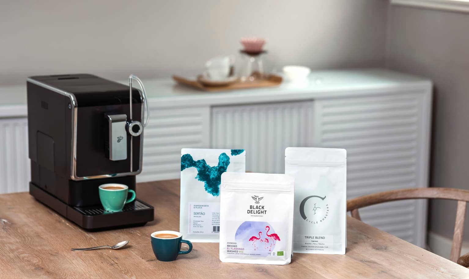 Drei Packungen Kaffee stehen neben dem Vollautomaten