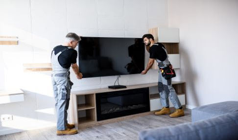 Zwei Techniker montieren einen Fernseher an der Wand.