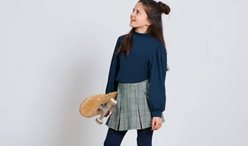 Zeitgemäß: Ein Mädchen mit einem Skateboard trägt einen karierten Hosenrock.