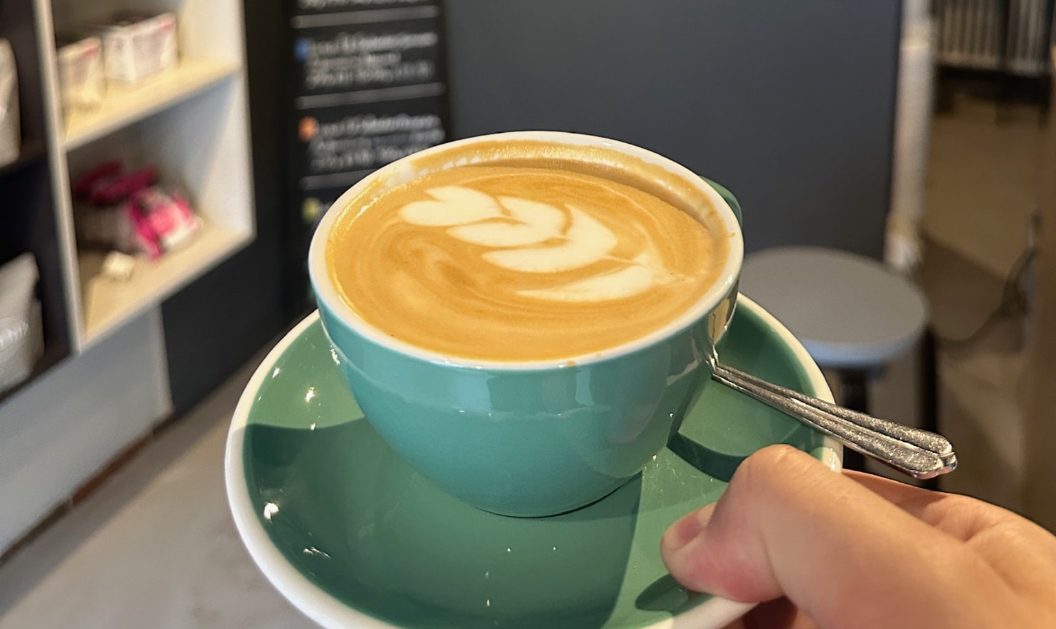 Tasse mit Cappuccino im Vordergrund, im Hintergrund das Logo von PHOENIX