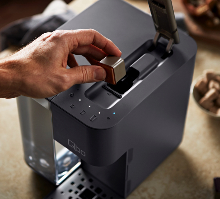 Ein Mann legt eine Qbo Kaffeekapsel in das Kapselfach einer Qb Touch in Basalt Grey