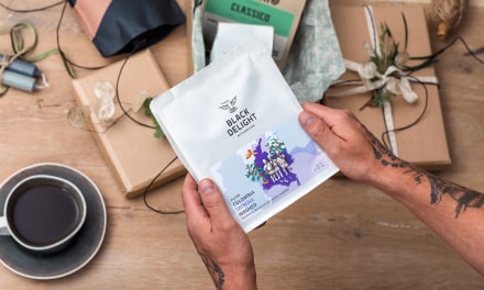 Specialty Coffee Kaffeeverpackungen liegen auf einem Holztisch und werden als Geschenk eingepackt.