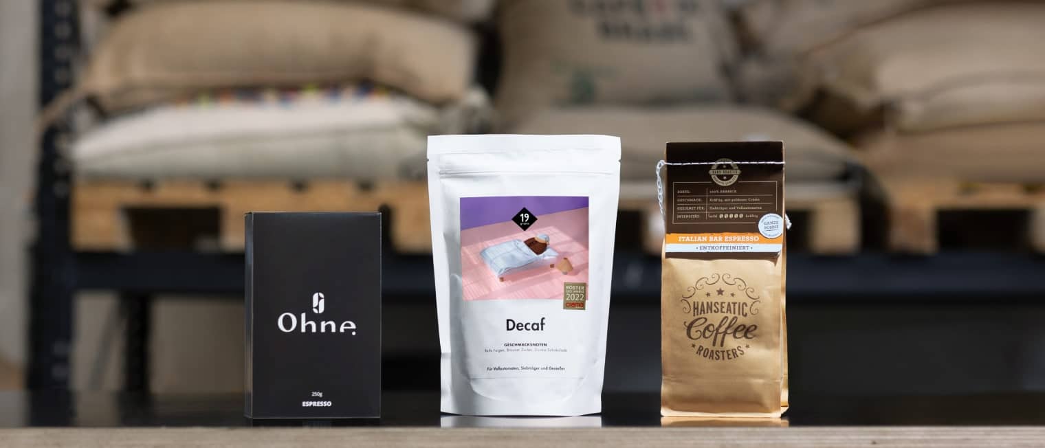 Drei Packungen entkoffeinierter Kaffee stehen auf einem Tisch.
