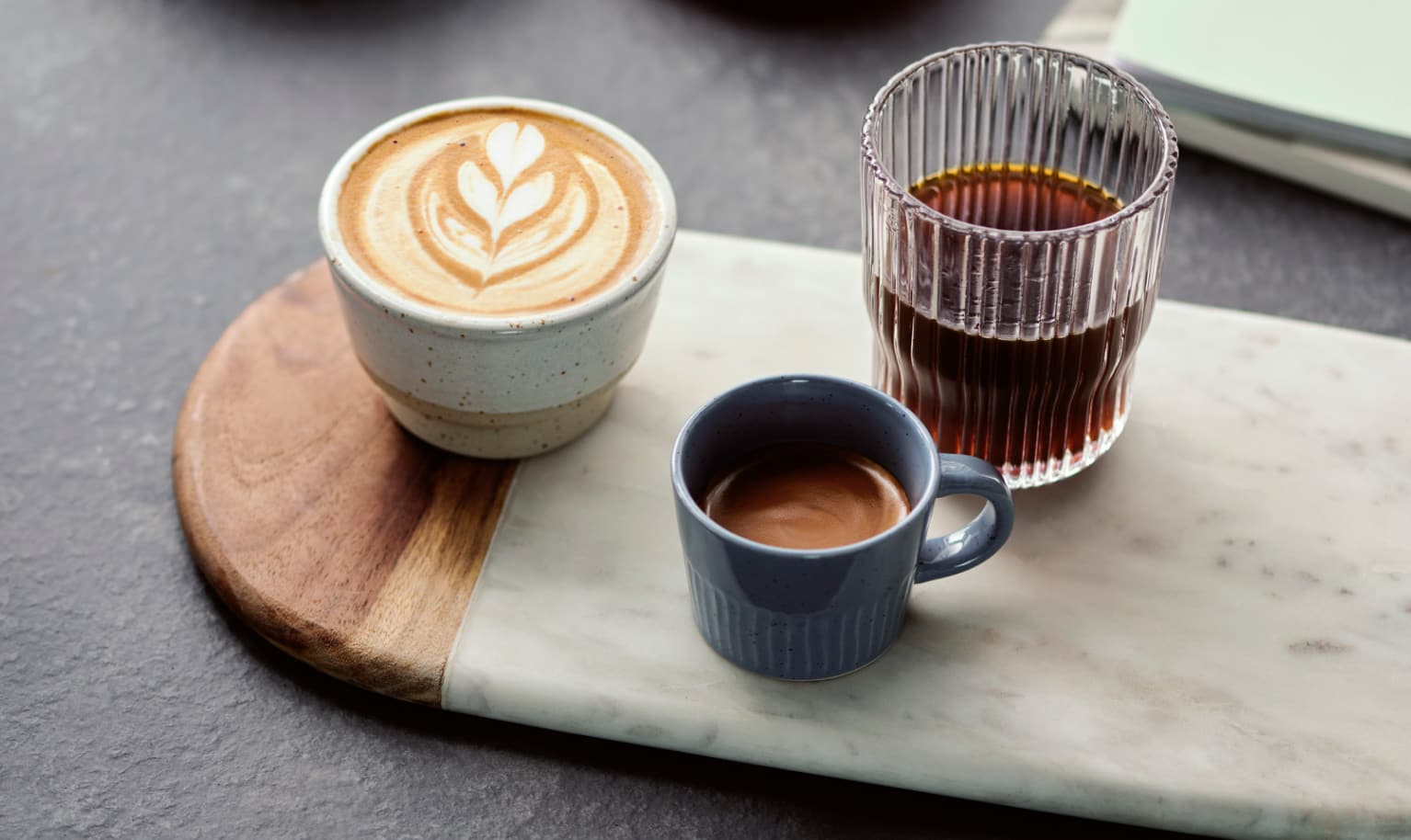 Cappuccino, Filterkaffee und Espresso stehen nebeneinander auf einer Küchentheke.