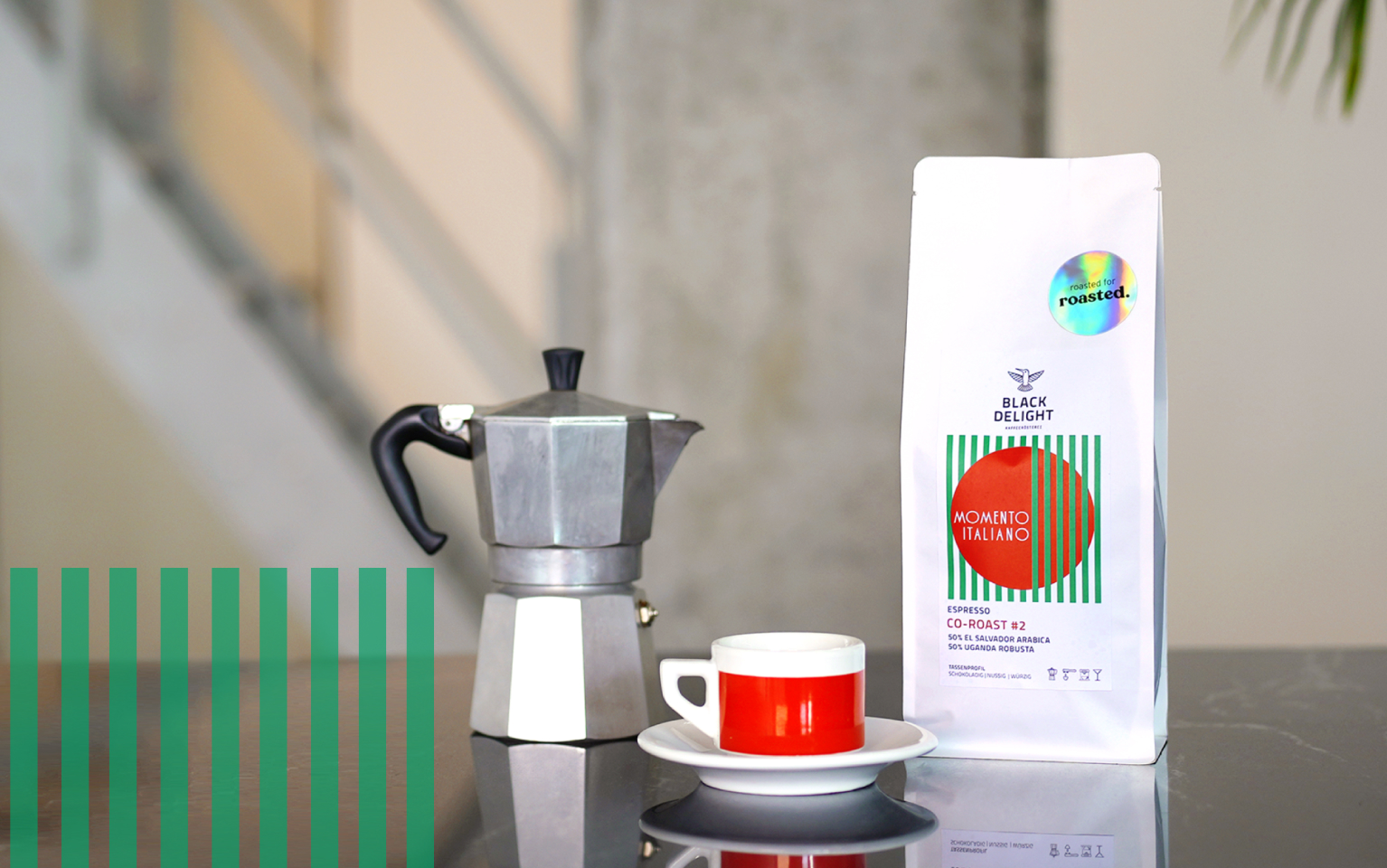 Eine Packung Momento Italiano Co-Roast #2 Espresso, eine Espressokanne und eine Espressotasse stehen auf einem Tisch