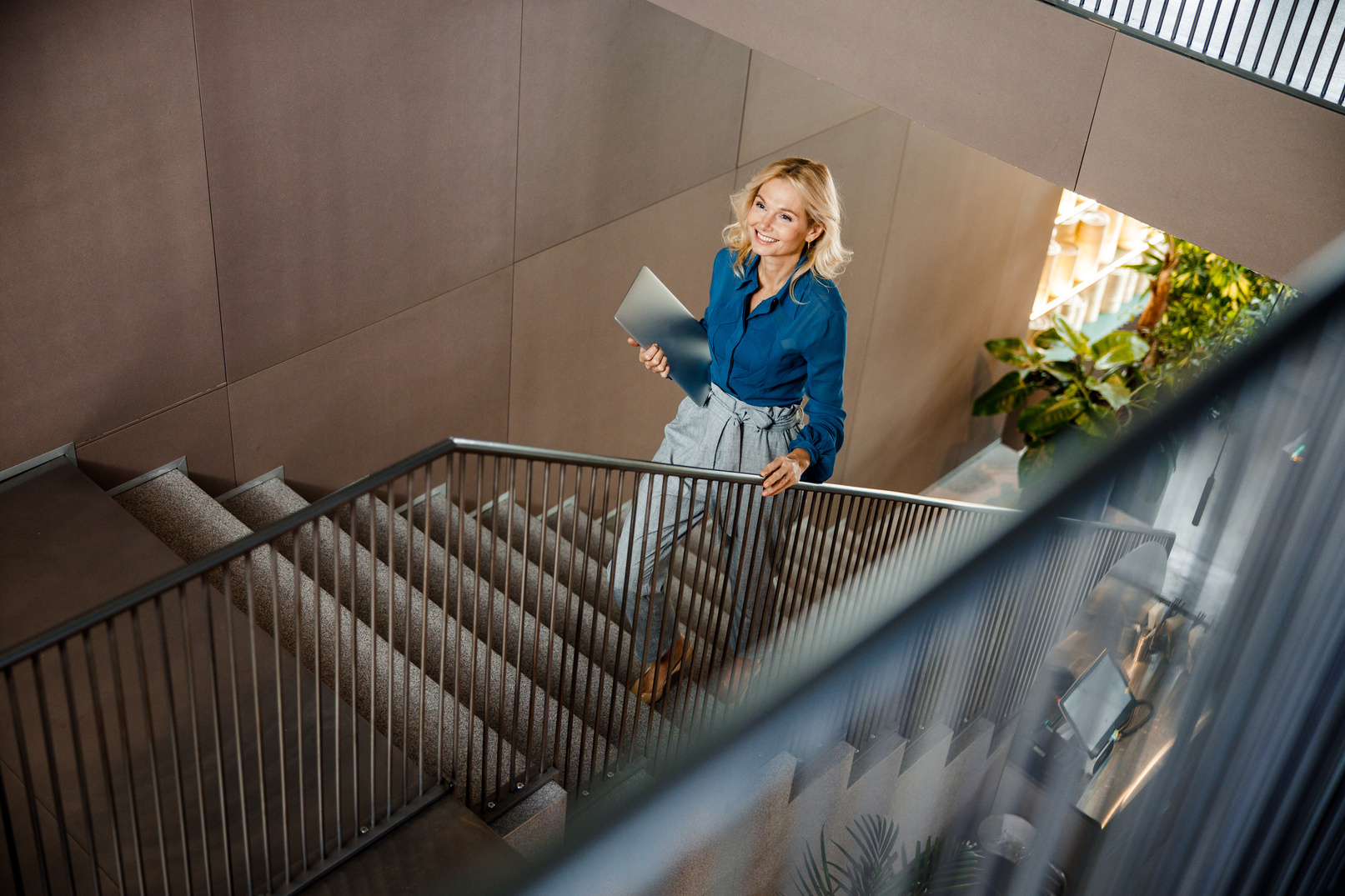 Fröhliche Dame mit Laptop auf der Treppe