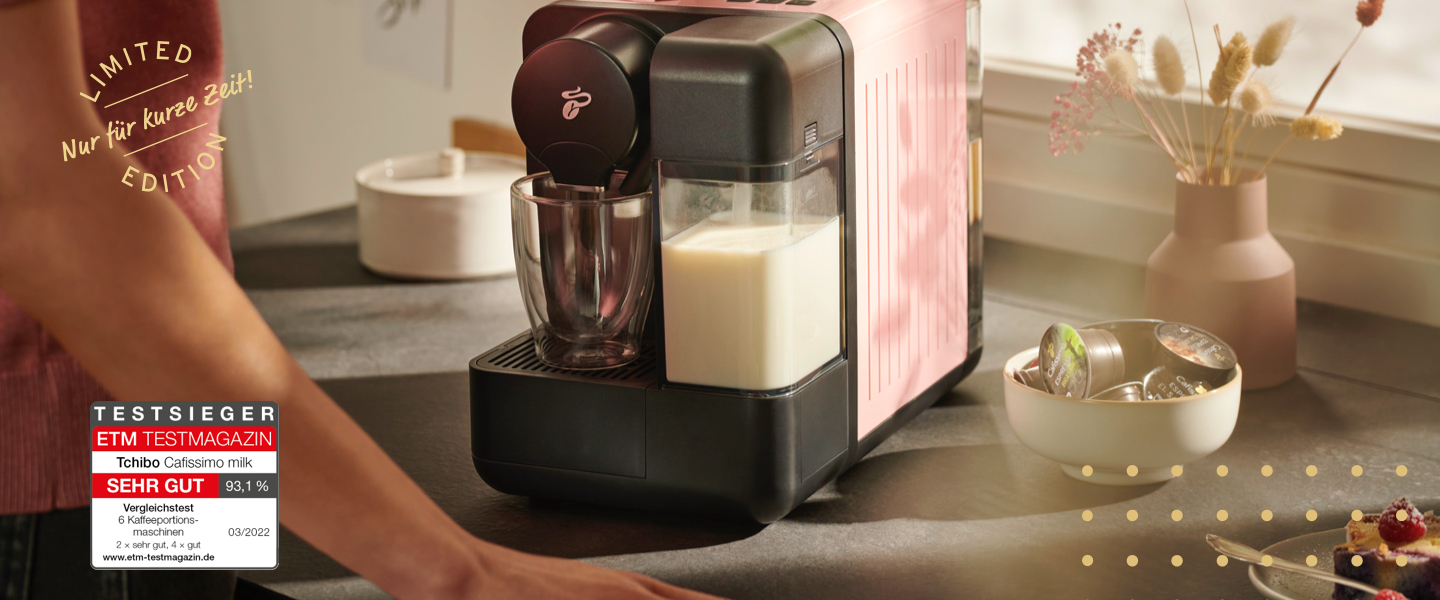 Die Cafissimo milk in weiß steht auf einer Küchentheke, im Hintergrund eine Blumenvase und eine Schüssel voller Cafissimo Kapseln