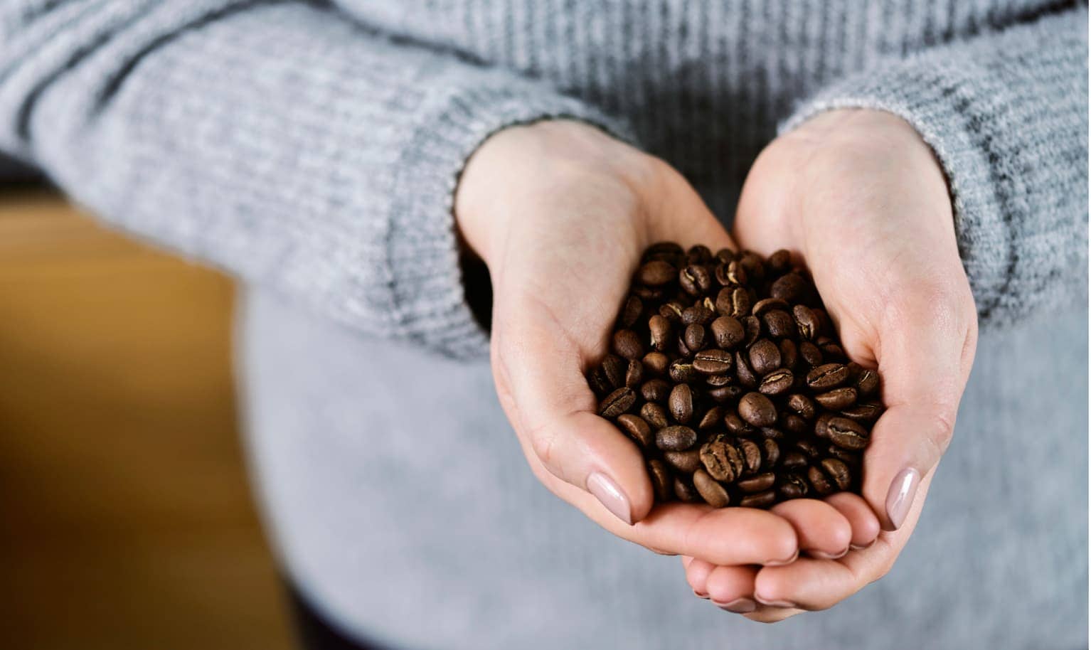Jemand hält viele Kaffeebohnen in den Händen