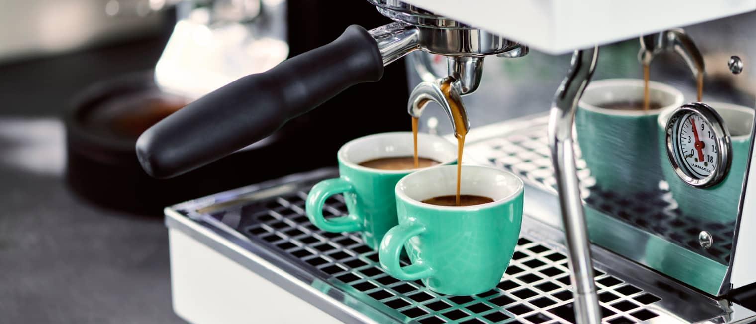 Espresso Tassen stehen unter einer Siebträgermaschine und es läuft ein Specialty Coffee Espresso in die Tasse.