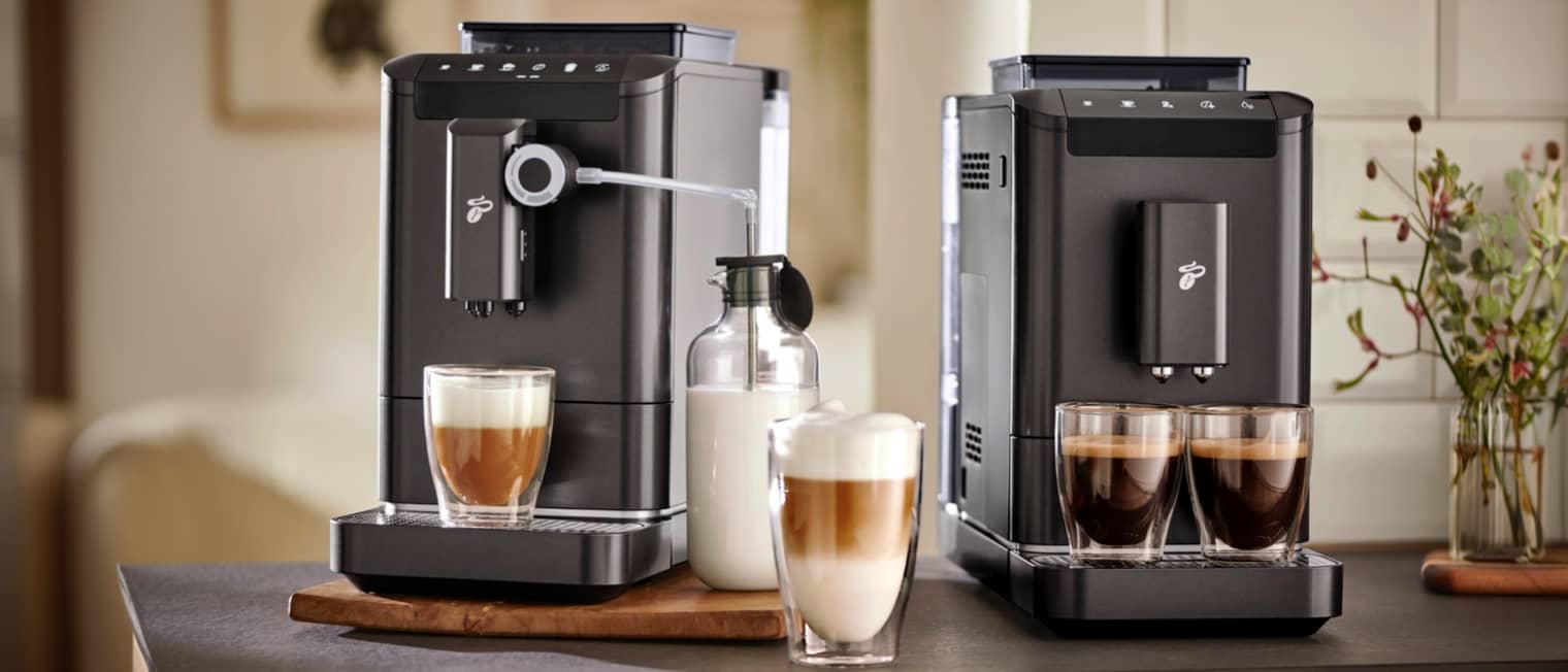 Drei hochwertige Kaffeevollautomaten stehen auf einer modernen Küchezeile.
