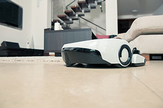 Elektrischer Helfer: Ein Saugroboter fährt über einen gefliesten Wohnzimmerboden.