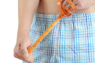 Nahaufnahme eines Mannes, der eine Boxershorts trägt, und ein Maßband in der Hand hält.