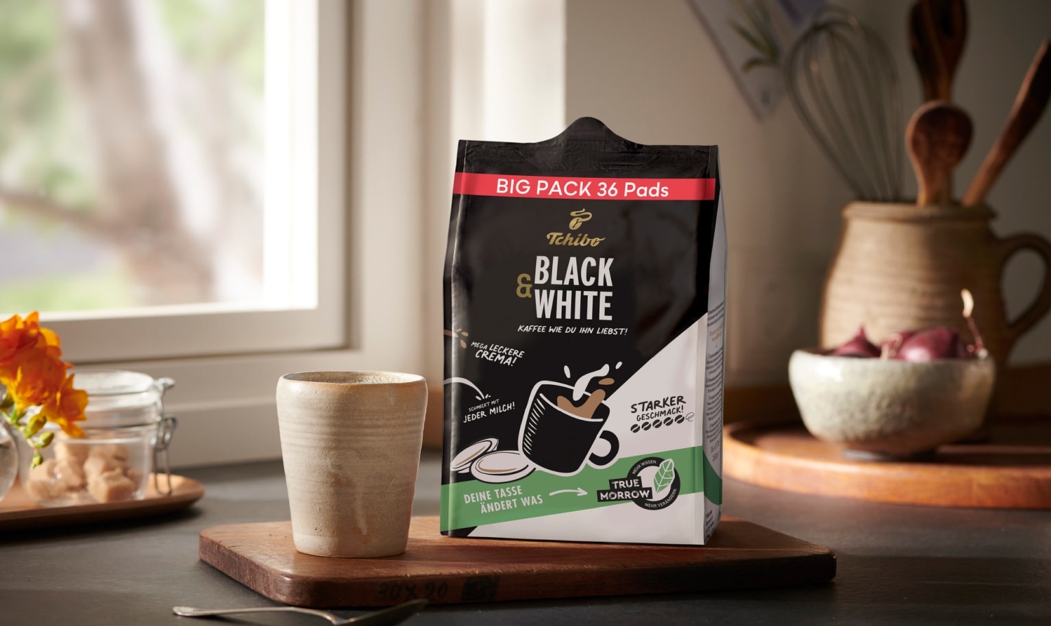 Auf dem tisch steht eine Packung BLACK & WHITE Kaffeepads.