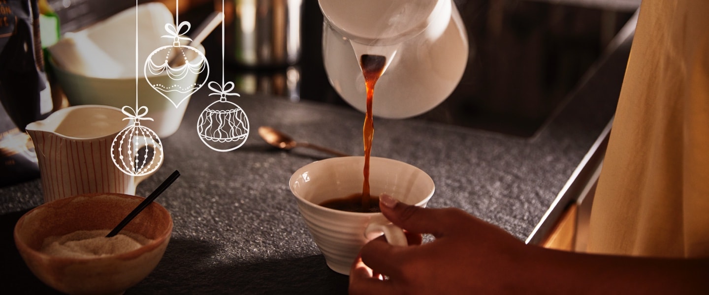 Stimmungsvolles Bild, in dem Kaffee aus einer Kanne in eine Tasse eingeschenkt wird.