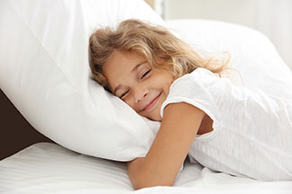Schlafzimmer Deko in guter Qualität: Eine junge Familie mit zwei kleinen Kindern albert gemeinsam im elterlichen Schlafzimmer auf dem Bett herum.