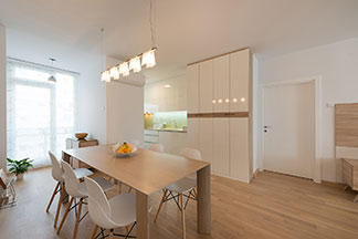 Richtige Deckenlampe in der Küche: Eine helle Küche mit einem rechteckigen Esstisch aus Holz über dem eine Deckenlampe mit fünf einzelnen Strahlern hängt.