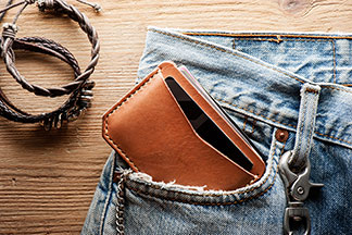 Portemonnaie in Tchibo-Qualität: Nahaufnahme einer Jeans. Aus deren Seitentasche schaut ein braunes Portemonnaie heraus.