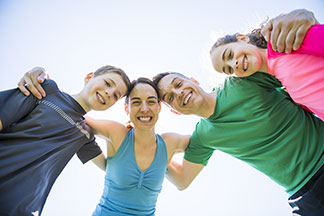 Eine junge Familie in Laufbekleidung umarmt sich und blickt zufrieden lächelnd in die Kamera.