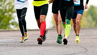 Nahaufnahme der Beine von vier Männern, die gerade joggen und dabei jeweils verschieden lange Herrensocken tragen.