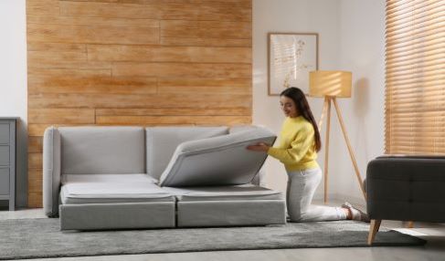 Ein Schlafsofa wird von einer Frau ausgezogen.