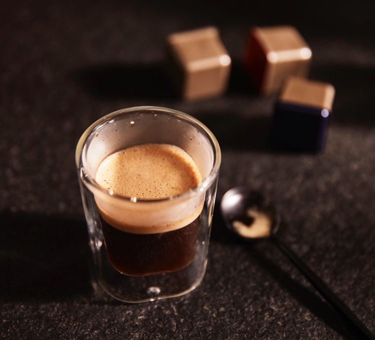 Stimmungsvolles Bild einer Tasse Espresso, die umgerührt wird.