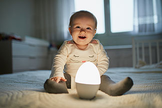 Ein Baby sitzt auf einem Bett mit einer Lampe.