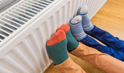 Zwei Teenager halten ihre Füße an eine Heizung. Sie tagen beide lange Ringelsocken.