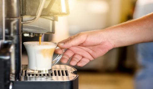 Mit schaumiger Crema: Aus einem Kaffeevollautomat fließt cremiger Kaffee in ein Glas.
