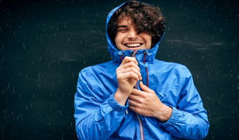 Dünne Regenjacken: Ein Mann in einer blauen Regenjacke steht im Regen und genießt die Tropfen auf seinem Gesicht.