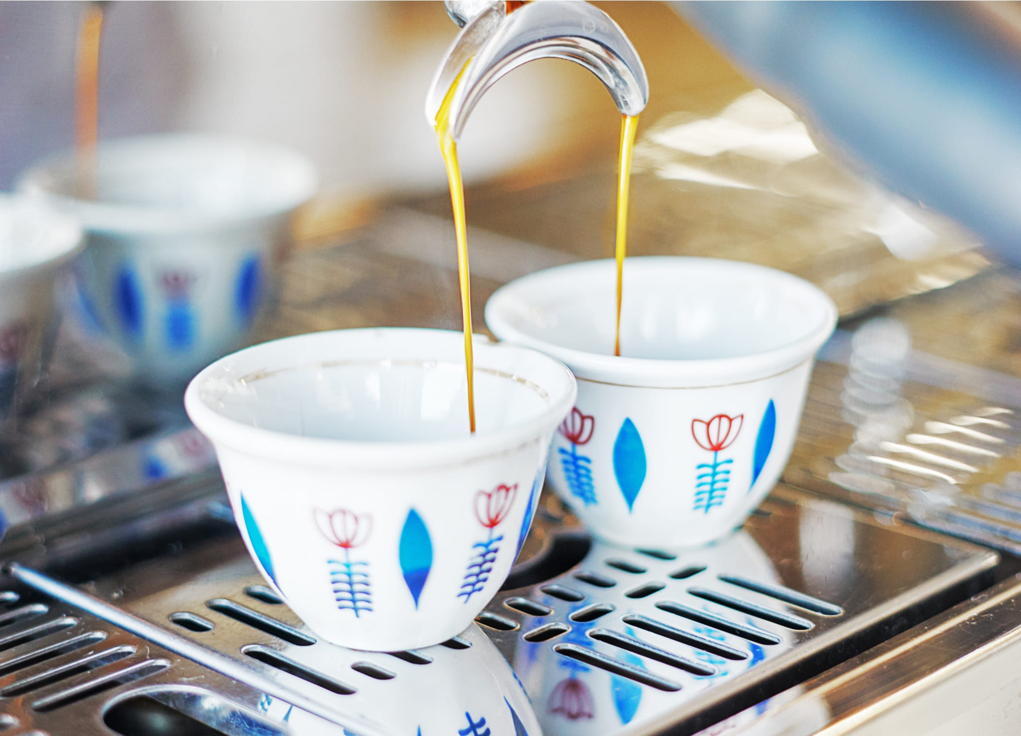 Zwei Espressitassen stehen unter einer Siebträgermaschine und Kaffee läuft ein