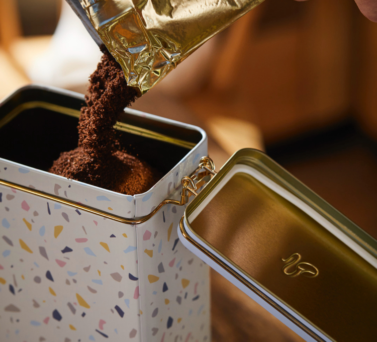 Eine geöffnete Aromadose, die mit Kaffeepulver gefüllt ist.
