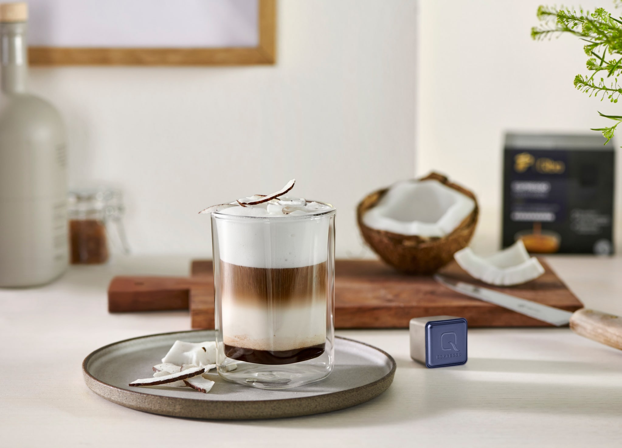 Glas Kaffee steht mit Kokosnussstücken auf Tisch