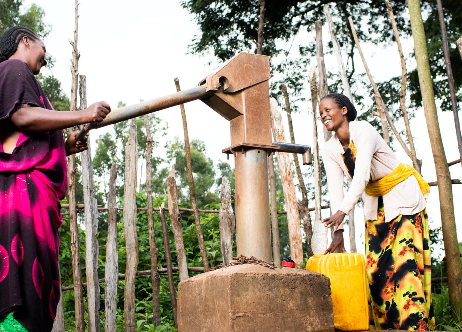 Zwei Farmerinnen pumpen Wasser