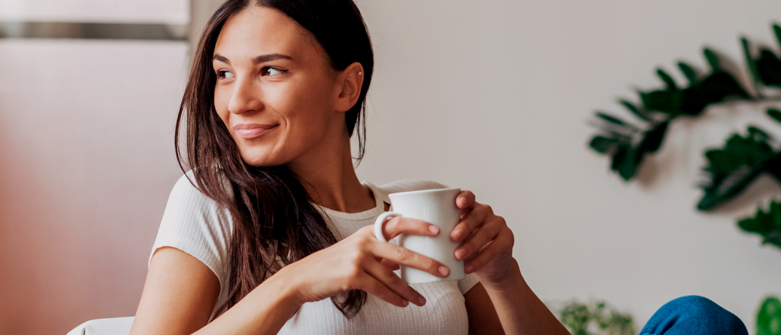 Eine Frau trinkt einen Kaffee auf dem Sofa aus einer Tasse.','Enter picture alt'}